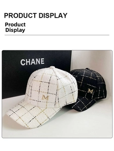 Detailed texture of white and black tweed baseball caps with golden metal M emblem