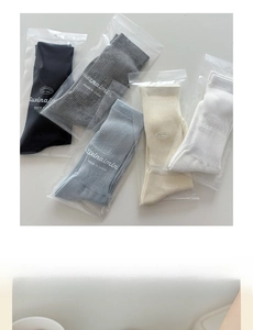 Detailed set of five ribbed knit crew socks in neutral tones with packaging pouches