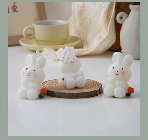 Detailed close-up of three cute white bunny scented candles with small red flower accents