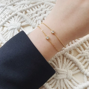 Détail de bracelets dorés avec diamants solitaires sur une manchette de costume bleu