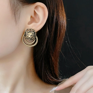 Détail de boucles d'oreilles tête de lion en or vintage portées par un mannequin en gros plan