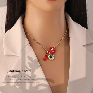 Close-up of gold chain necklace featuring evil eye charm and red coral pendant on model