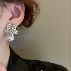 Close-up of elegant flower earring with zircon crystals and a white pearl on a model