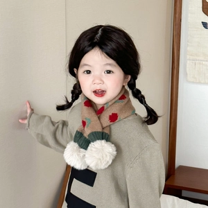 Detail of brown knitted kids scarf with red polka dots and white pom-pom detail