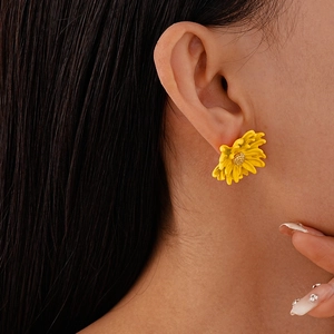 Close-up of a yellow daisy flower stud earring on model with golden stamen detail