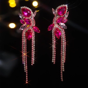 Macro detail of luxury magenta rhinestone tassel earrings with shimmering bokeh background