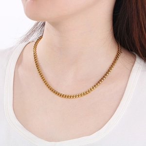 Close-up of a gold-plated Cuban link necklace on a male model wearing a white shirt