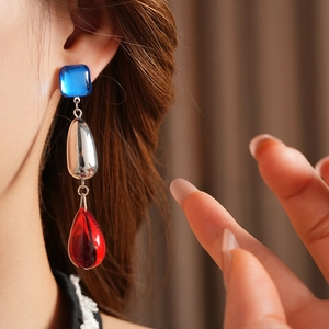 Macro view of vintage water drop tassel earrings with blue and red resin stones