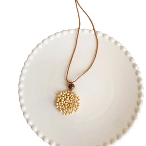 Bohemian wax cord necklace with handmade wood bead heart pendant on white ceramic plate