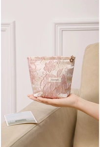 Close-up of pink embossed floral makeup bag with elegant metal flower zipper pull