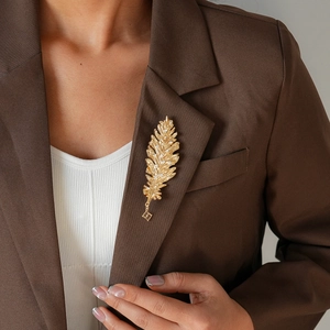 Close-up of golden feather brooch with crystal rhinestones on a dark brown blazer lapel