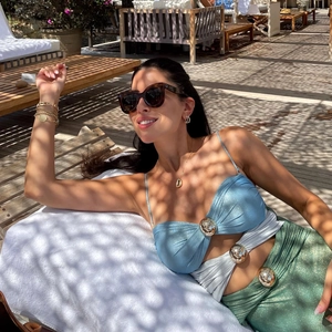 Close-up of shiny fabric bikini with a large gold metal buckle on a sunlit lounger
