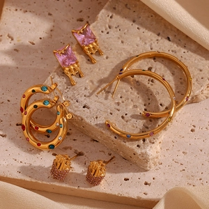 Detailed close-up of 18K gold earrings with colorful zircon on stone and silk