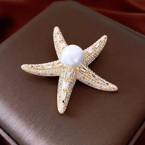 Macro detail of 14K gold plated starfish brooch with pearls and sparkling crystals