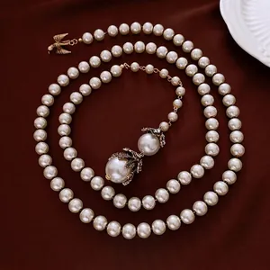 Elegante collana di perle vintage a doppio strato con ciondolo ad aquila dorata e dettagli floreali