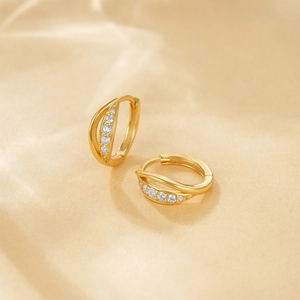 Close-up of gold s925 silver huggie hoops with sparkling diamonds on beige paper