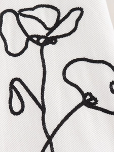 Macro detail of black floral embroidery on premium white twill fabric texture