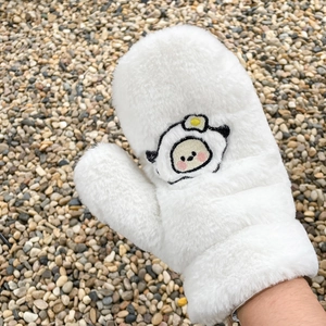 Close-up of white plush mittens with cute sheep embroidery on a pebble ground