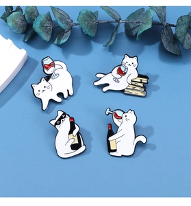 Detail of four cartoon white cat enamel pins featuring wine bottles and glasses