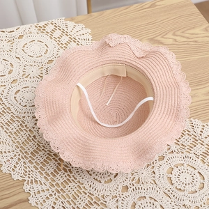 Dettaglio del cappello di paglia rosa per bambina con tesa ondulata e cordino elastico