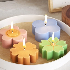 Candele profumate a forma di fiore in quattro colori su un vassoio decorativo