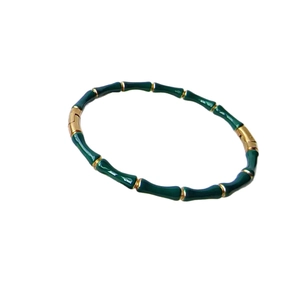 Bamboo style bracelet with green enamel and 18k gold plating on white background