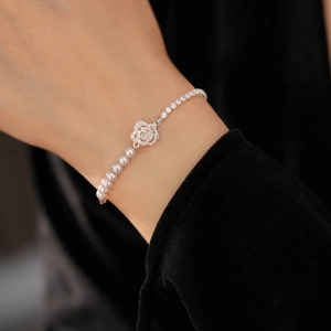 Detail of zircon rose flower bracelet with pearls shown on wrist with elegant black background