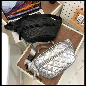 Detailed view of quilted puffer waist bags in black and silver on a desk setting