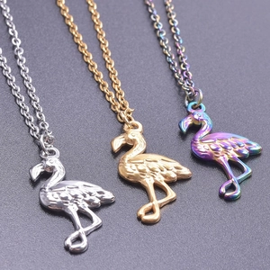 Macro shot of flamingo pendants in silver, gold, and rainbow finishes showing feather details