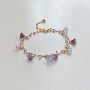Detail shot of a golden flower necklace with purple and clear crystal beads and lobster clasp