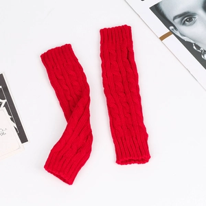 Detail of red cable knit arm warmers showing thick wool texture on white background