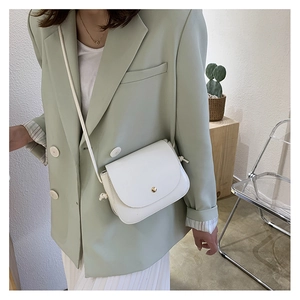 Detailed view of a white leather crossbody bag featuring a chic metal buckle on a flap