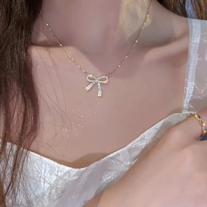Close-up of elegant gold bow pendant necklace with sparkling cubic zirconia on model