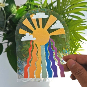 Close-up of holographic suncatcher window sticker with sun and rainbow design