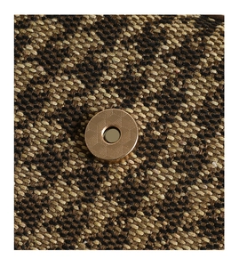 Macro shot of gold magnetic clasp on houndstooth fabric for shoulder bag detail
