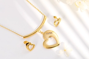 Detail of gold heart necklace and earrings set with inlaid diamonds on white floral background