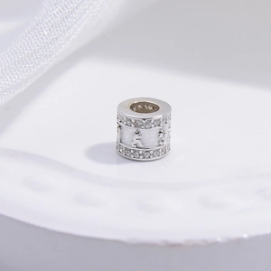 Macro shot of silver cylinder bead with white zircon inlay and mantra engraving