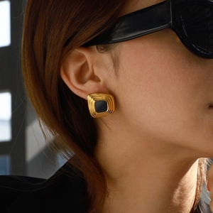 Detail of vintage square resin earrings in gold and black on model with sunglasses