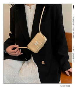 Détail d'un mini sac doré avec un ornement papillon blanc et une texture en cuir métallisé