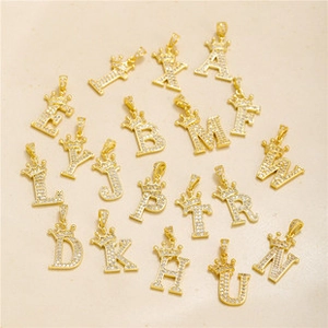 Macro detail of 18k gold plated crown letter charms with micro-paved cubic zirconia stones
