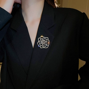 Close-up of a hollow rose brooch with sparkling crystals on a black suit jacket