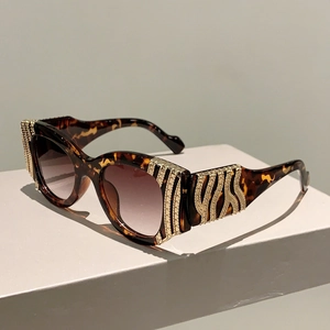 Detail of tortoise shell sunglasses with gold metal accents on white geometric base