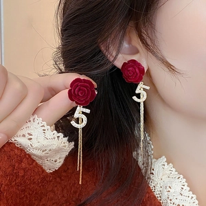 Détail de boucles d'oreilles rose rouge avec numéro 5 en perles et longues pampilles