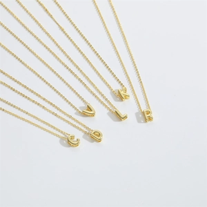 Macro view of polished gold-tone alphabet pendant necklaces with delicate chain detail