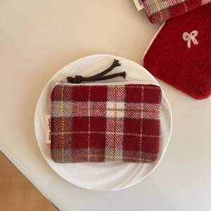 Detail view of red plaid tweed pouch with zip cord and simple wish woven label