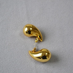 Macro view of gold-plated hollow teardrop earrings with high-gloss mirror finish