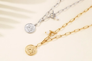 Detailed view of paperclip chain necklaces with angel coin pendants and pearl toggle clasps