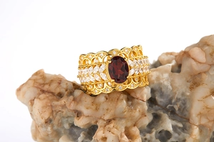 Macro shot of luxury S925 silver wide ring with garnet and topaz on natural rock base