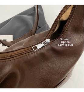 Detail of smooth silver metal zipper on vintage dark brown lychee texture leather tote bag