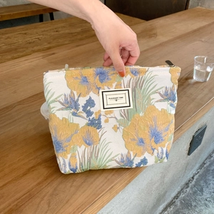 Detail van brokaat make-uptas met bloemmotieven en een Pleasant Time-stoffen label